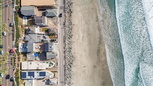 Vista aérea de una zona residencial costera con casas, una carretera y una playa.