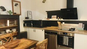 Eine kleine Küche mit Holztisch, Spüle, Herd und Geschirrspüler.