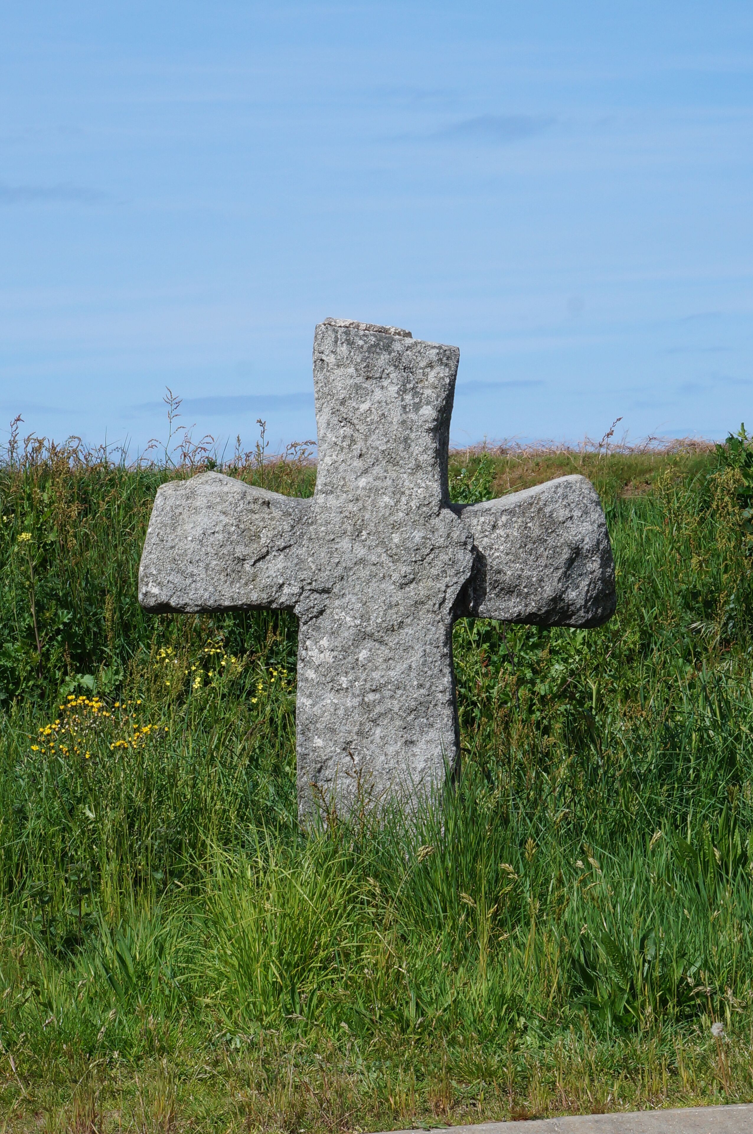 A large stone cross in a grassy field.