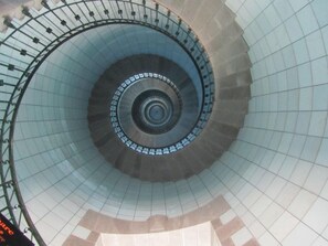 Uma escadaria em espiral com proteção de vidro e corrimãos de metal.