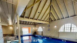 An indoor swimming pool with a high, sloped ceiling and wooden paneling. - Waterfront Lodge 4 with Hot Tub (Kentallen Pier)