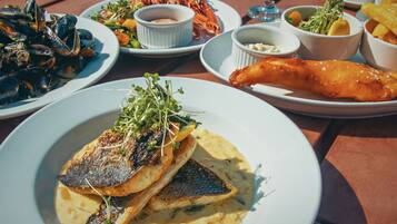 A variety of seafood dishes including mussels, lobster, and fish, served on a wooden table.