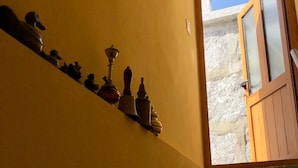 Una escalera con un muro de piedra a un lado y una puerta de madera que da al exterior.