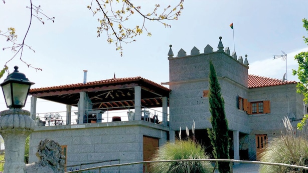 Un edificio de piedra con una torre, un porche cubierto y una estatua al frente.