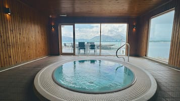 Un bain à remous avec vue sur une étendue d’eau et des montagnes au loin.