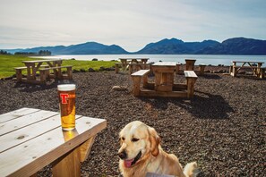 A beach with wooden picnic tables and a glass of beer. - Waterfront Lodge 6 with Hot Tub (Kentallen Pier)