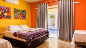 A hotel room with a bed, a small table, a chair, and a window with curtains. - Pousada Amarante praia (São Miguel do Gostoso)