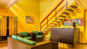 A bright living room with wicker furniture, a staircase, and artwork on the walls. - Pousada Amarante praia (São Miguel do Gostoso)