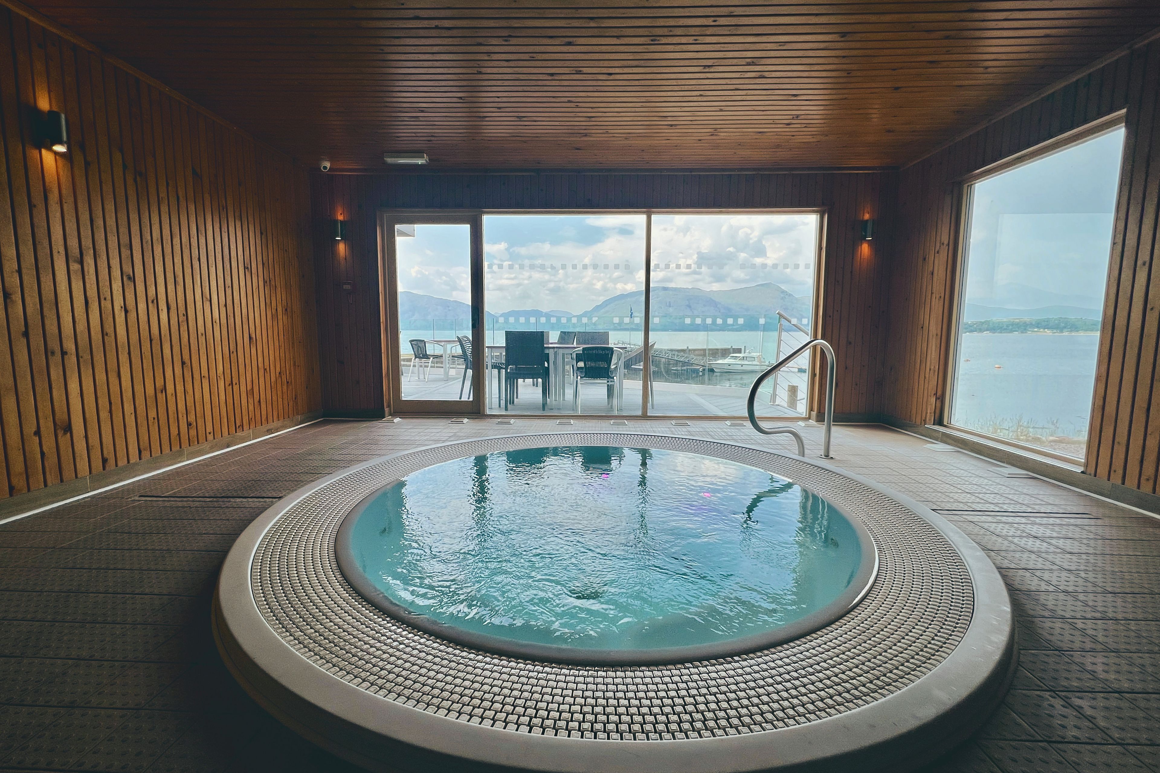 A hot tub with a view of a body of water and mountains in the distance.