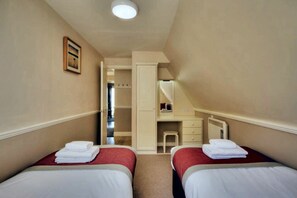 A hotel room with two beds, a desk, and a mirror.