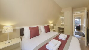 Een hotelkamer met een groot bed, een nachtkastje met een lamp, een kledingkast en uitzicht op buiten.
