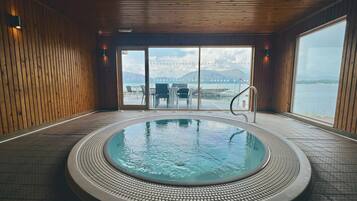 A hot tub with a view of a body of water and mountains in the distance.