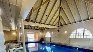 An indoor swimming pool with a high, sloped ceiling and wooden paneling.
