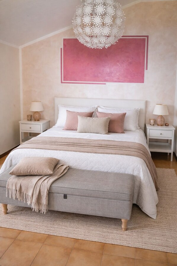 A bedroom with a large bed, two bedside tables, a decorative chandelier, and a large abstract painting on the wall. - B&B Musik Suite with a View of Lake Garda (Torri del Benaco)
