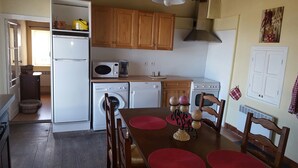 A compact kitchen with wooden cabinets, a microwave, a stove, and a washing machine. - House in Taulis Catalan in the hinterland near Perpignan (Taulis)
