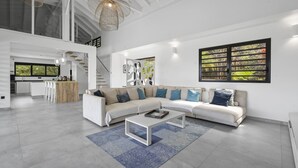 Een ruime woonkamer met een grote hoekbank, een salontafel en een moderne kroonluchter.