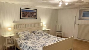 A bedroom with a bed, bedside tables, a chair, a window, and a picture on the wall. - 🌊 Holiday home for 6 in Grömitz | 2 bathrooms, garden & beach chair on the beach (Grömitz)