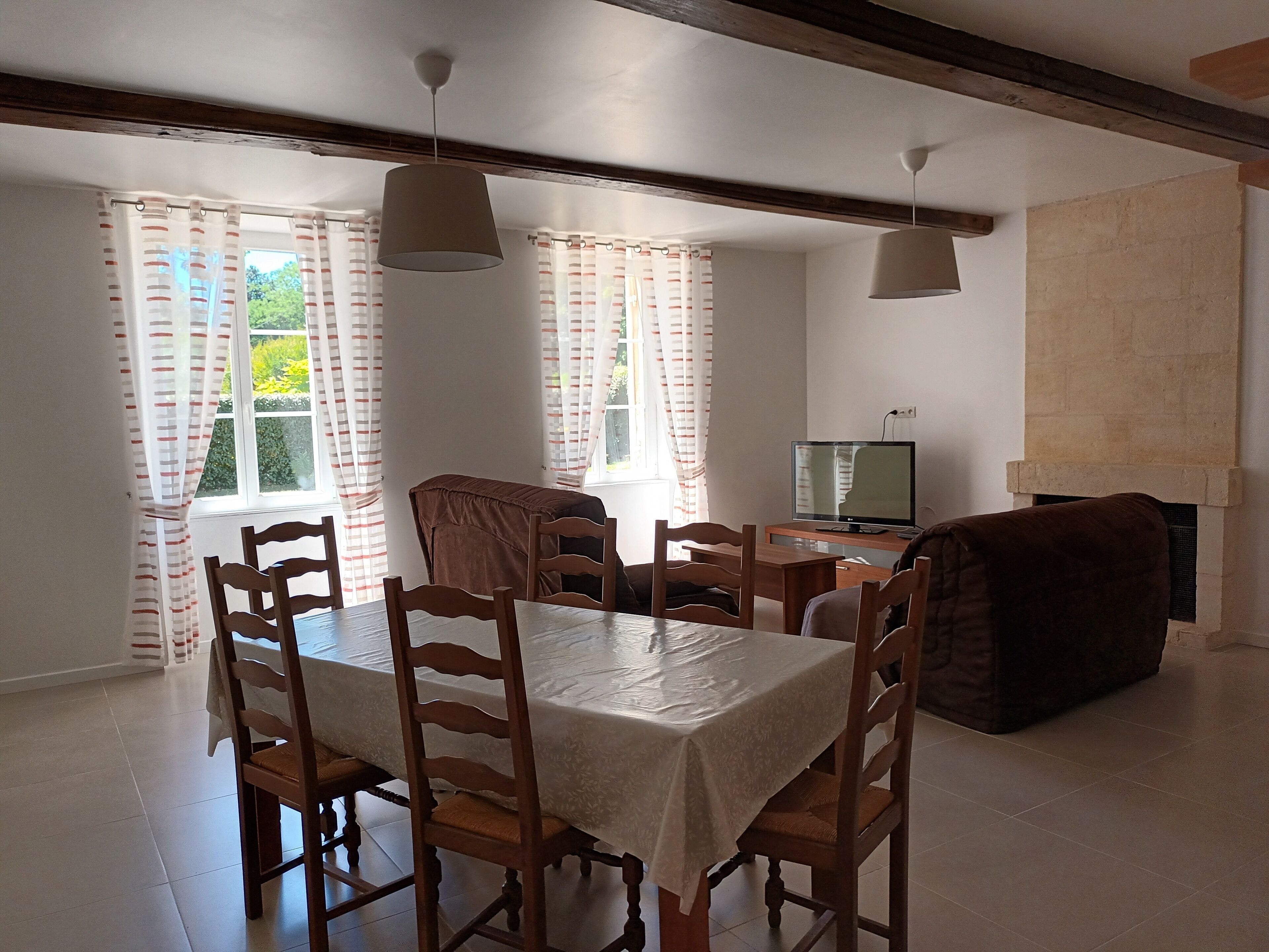 Zona pranzo con tavolo e sedie, una televisione e un camino.