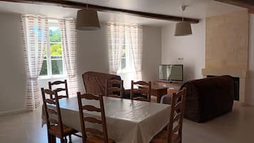 Zona pranzo con tavolo e sedie, una televisione e un camino.