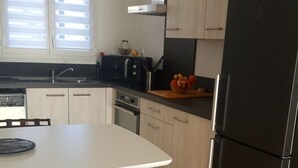 Cozinha moderna com mesa de jantar, cadeiras, geladeira e janela com persianas.