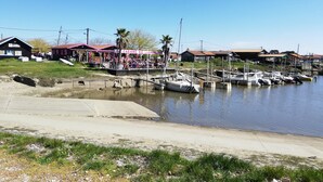 Uma marina com barcos atracados, uma área coberta com pessoas e edifícios ao fundo.