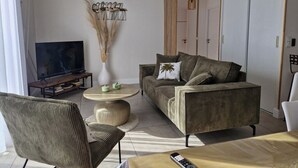Uma sala de estar moderna com um sofá, uma mesa de centro, uma televisão e um vaso decorativo.