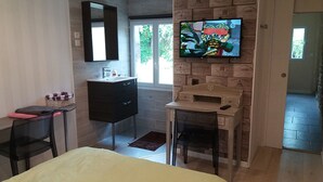Un dormitorio moderno con cama, tocador con espejo, televisor en la pared y escritorio con silla.