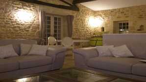 Una sala de estar acogedora con paredes de piedra, una chimenea y dos sofás con cojines.