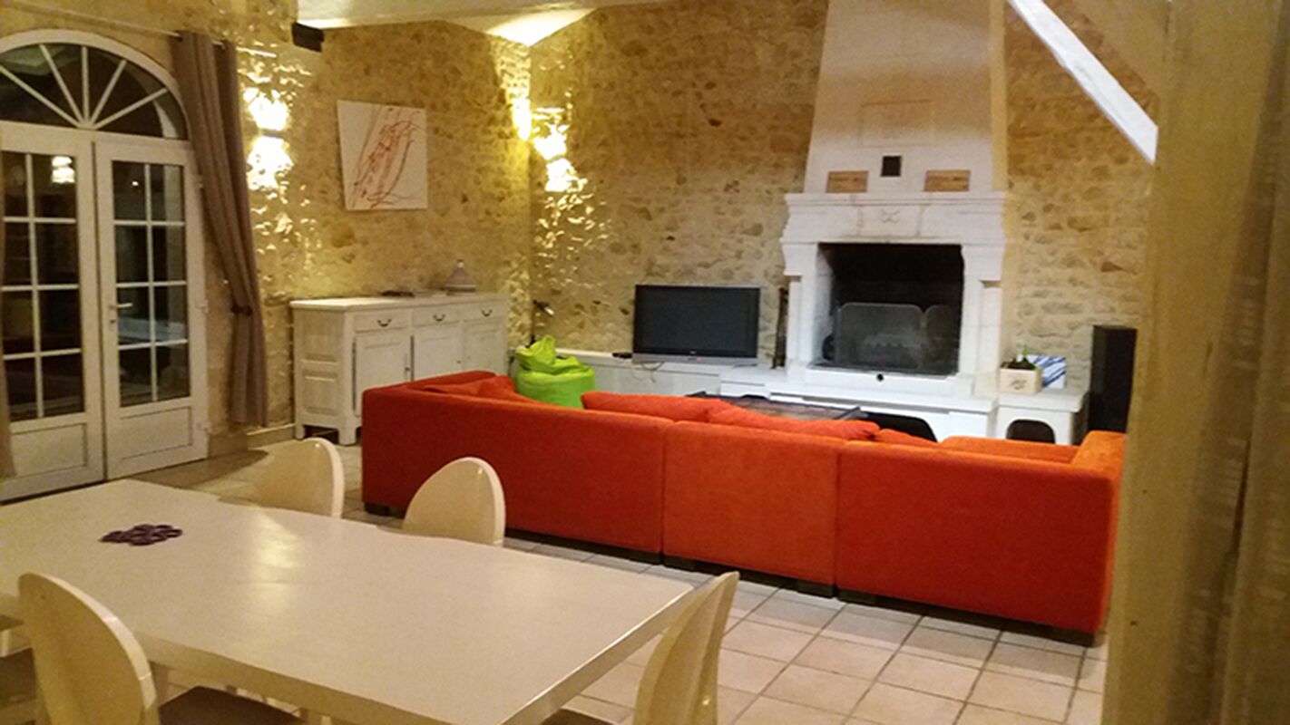 A cozy kitchen with a stone wall, a fireplace, and a red sofa.