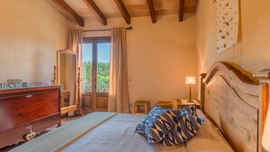A bedroom with a wooden headboard, a bed with patterned pillows, a dresser with a heart-shaped drawer, and a window with curtains. - Sa Tanqueta Rustica, Country House 5StarsHome Mallorca (Inca)