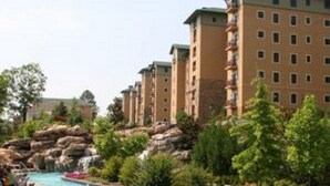 Un hotel con una amplia piscina exterior rodeada de exuberante vegetación y un paisaje rocoso.