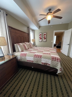 A bedroom with a bed, a nightstand, a lamp, a ceiling fan, and a door leading to another room. - CLEARLY THE BEST RIGHT HERE (Pigeon Forge)