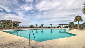 A swimming pool with a pergola and palm trees in the background.