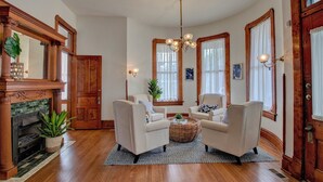 A traditional living room with a fireplace, two armchairs, a coffee table, and a chandelier. - The Baker (North Little Rock)