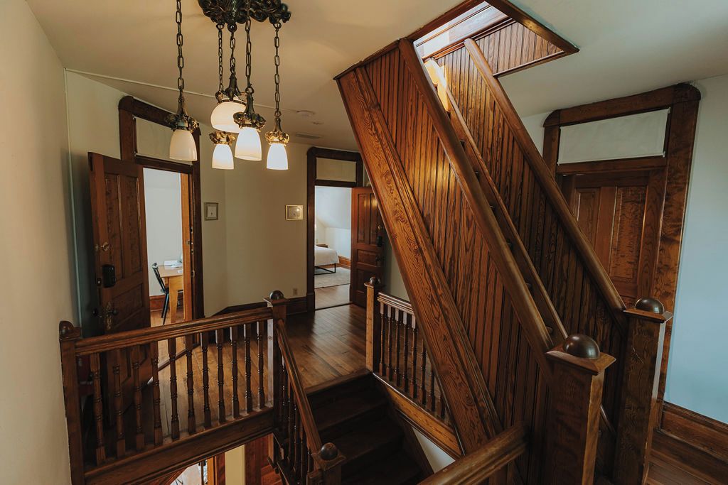 A wooden staircase with a handrail and a light fixture above.