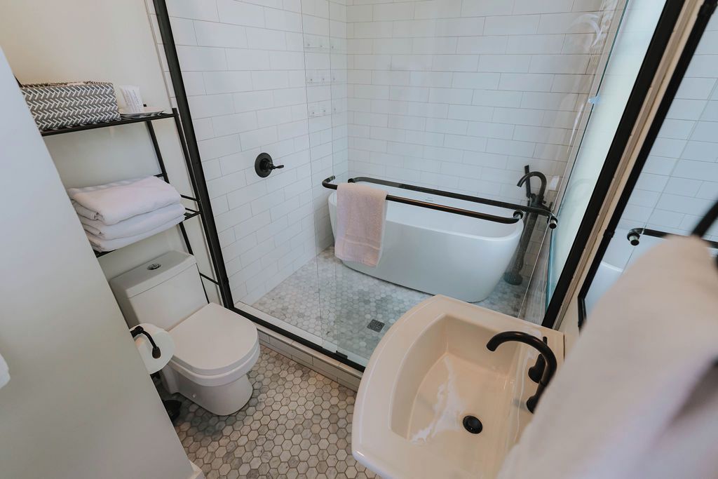 A bathroom with a toilet, sink, shower, and a glass-enclosed shower stall.