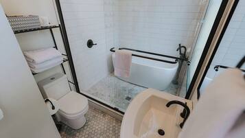 A bathroom with a toilet, sink, shower, and a glass-enclosed shower stall.