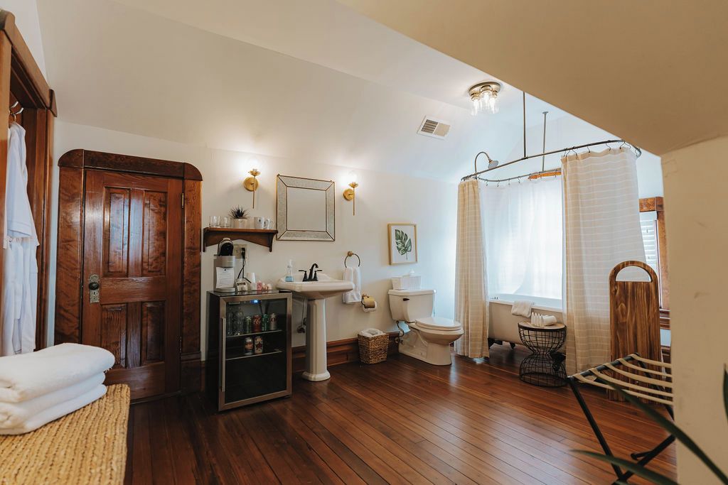 A bathroom with a wooden floor, a sink, toilet, and a shower area.