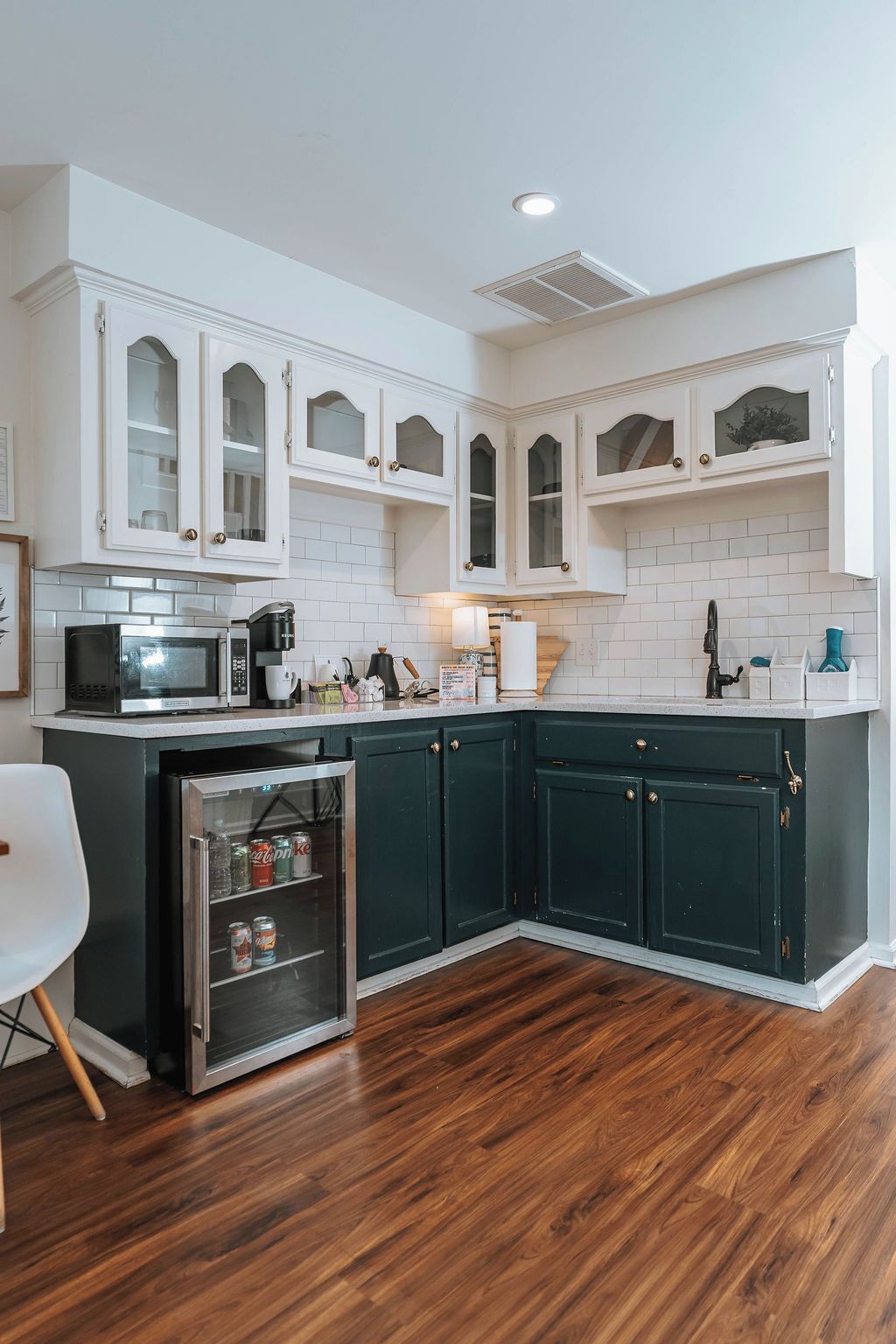 Una cocina con armarios blancos, microondas, cafetera y refrigerador.