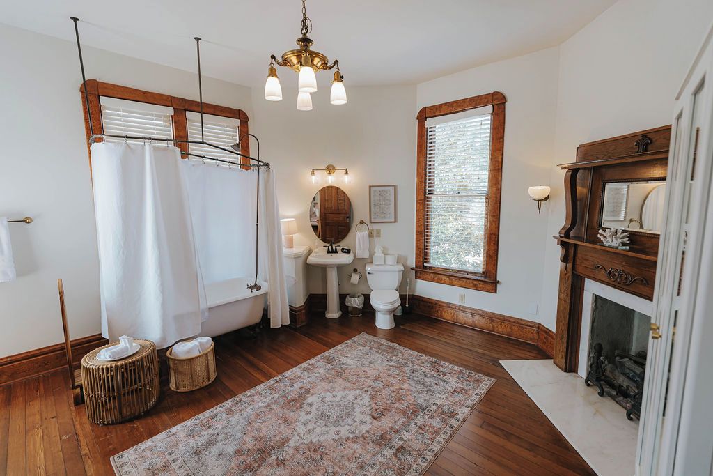A bathroom with a bathtub, a sink, a mirror, and a fireplace.