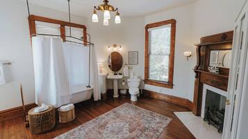 A bathroom with a bathtub, a sink, a mirror, and a fireplace.