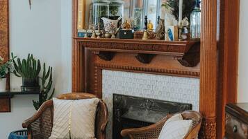 A room with a fireplace, two upholstered chairs, a mirror, and various decorative items on the mantel.