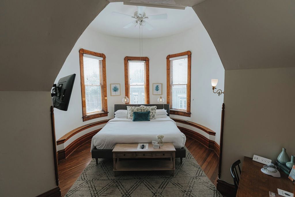 Quarto com cama, escrivaninha e ventilador de teto.