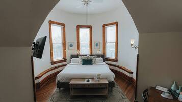 Quarto com cama, escrivaninha e ventilador de teto.