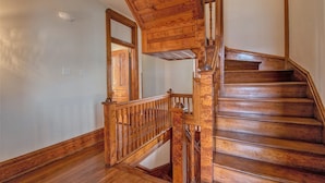 A wooden staircase with a handrail and a landing area. - The Baker (North Little Rock)
