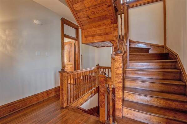 A wooden staircase with a handrail and a landing area. - The Baker (North Little Rock)