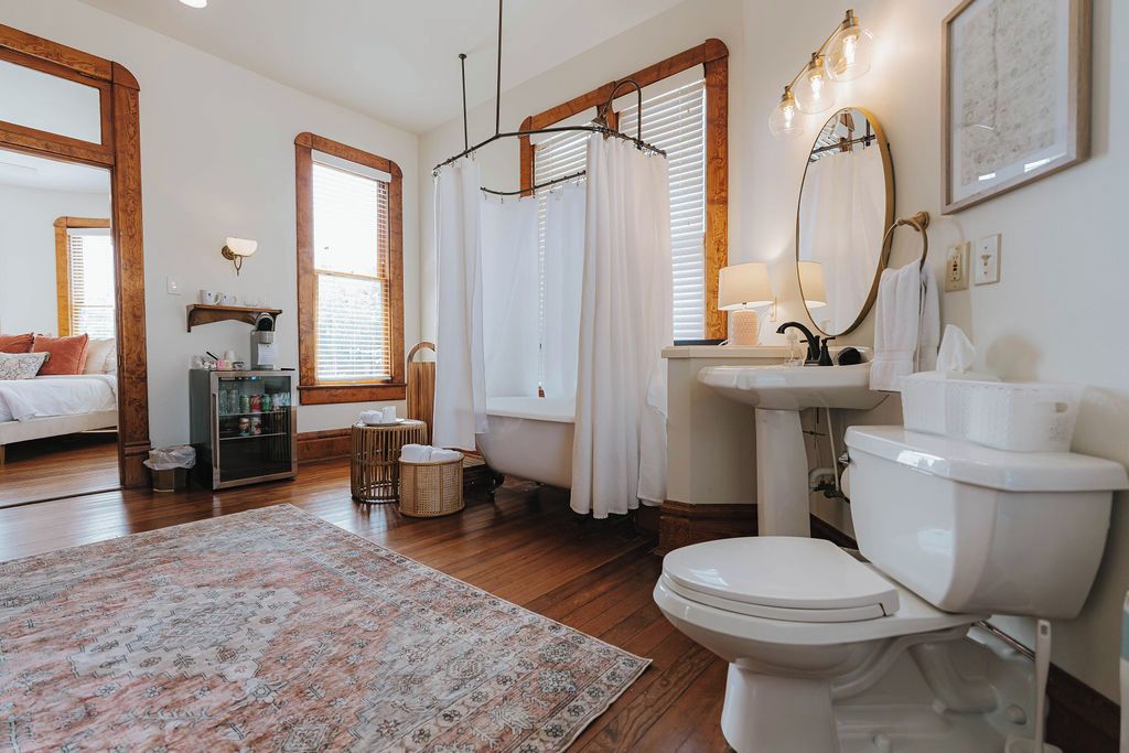A bathroom with a bathtub, toilet, sink, and a large mirror.
