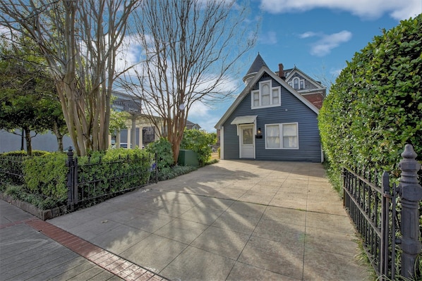 A residential house with a front yard, a paved driveway, and a black metal fence. - The Baker (North Little Rock)
