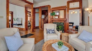 A spacious living room with a fireplace, wooden furniture, and a staircase leading to another level. - The Baker (North Little Rock)