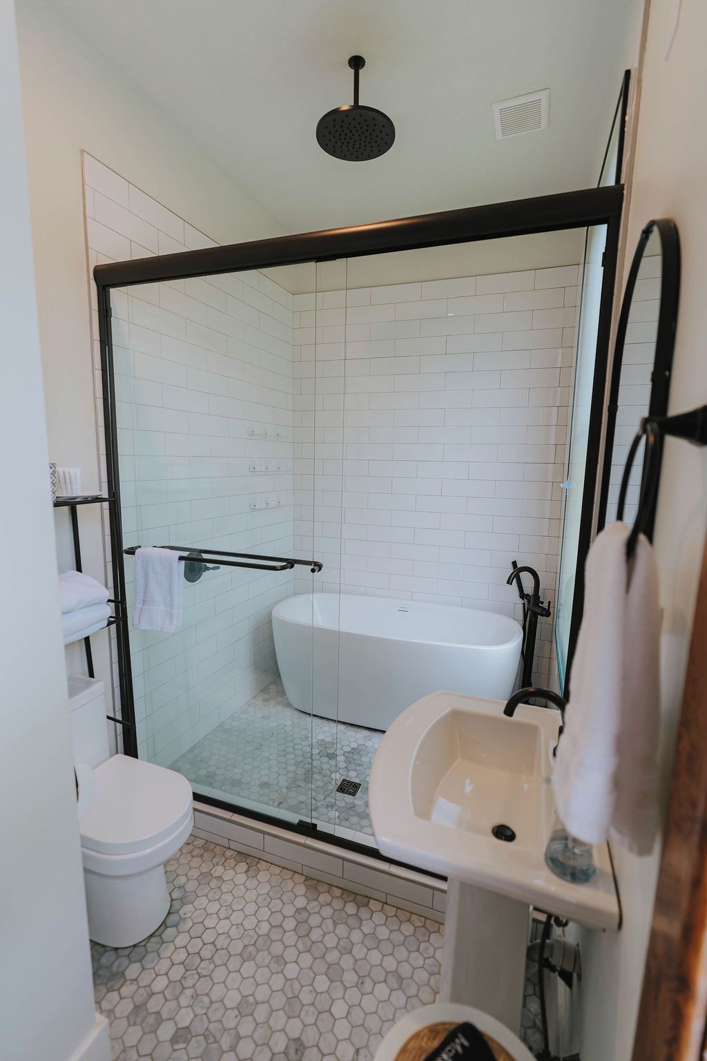 A modern bathroom with a glass-enclosed shower, a white bathtub, and a sink.